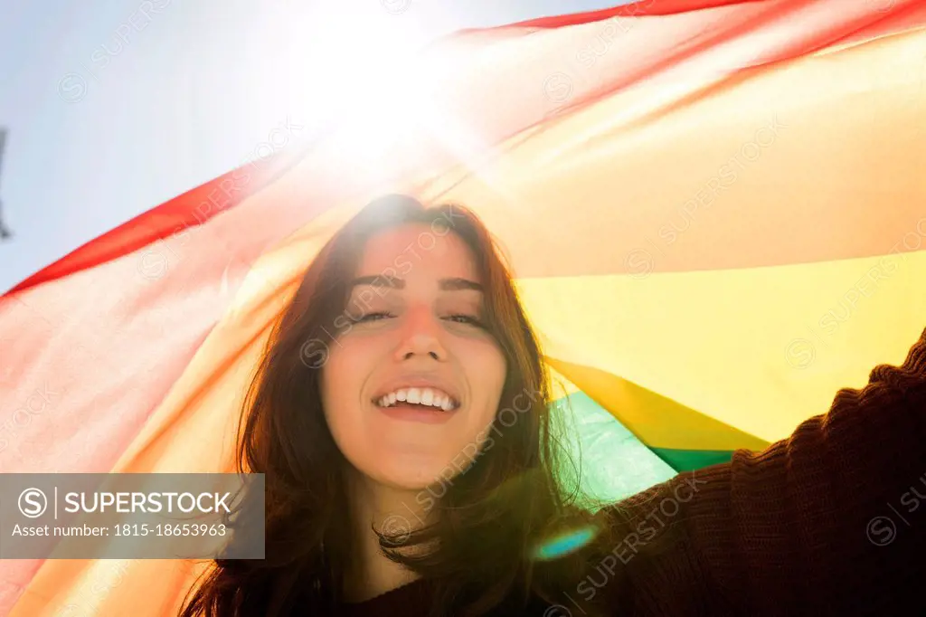 Young woman with rainbow flag during sunny day
