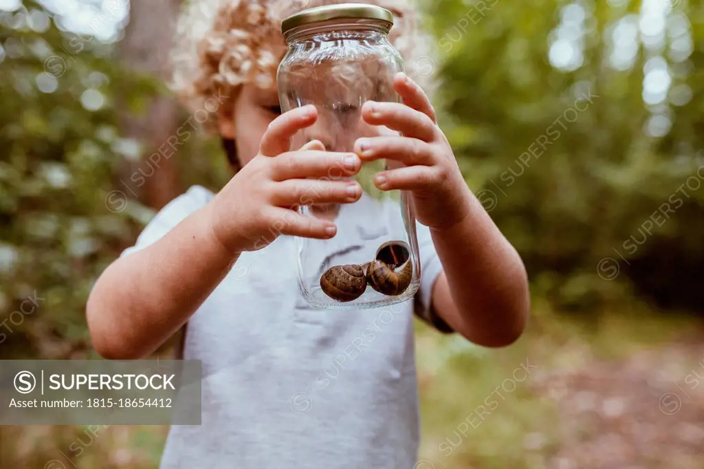 Boy holding glass jar with snails