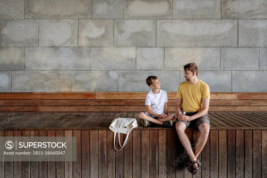 Boy talking with father while sitting on bench