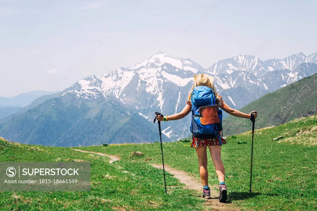 Female backpacker hiking on mountain during sunny day