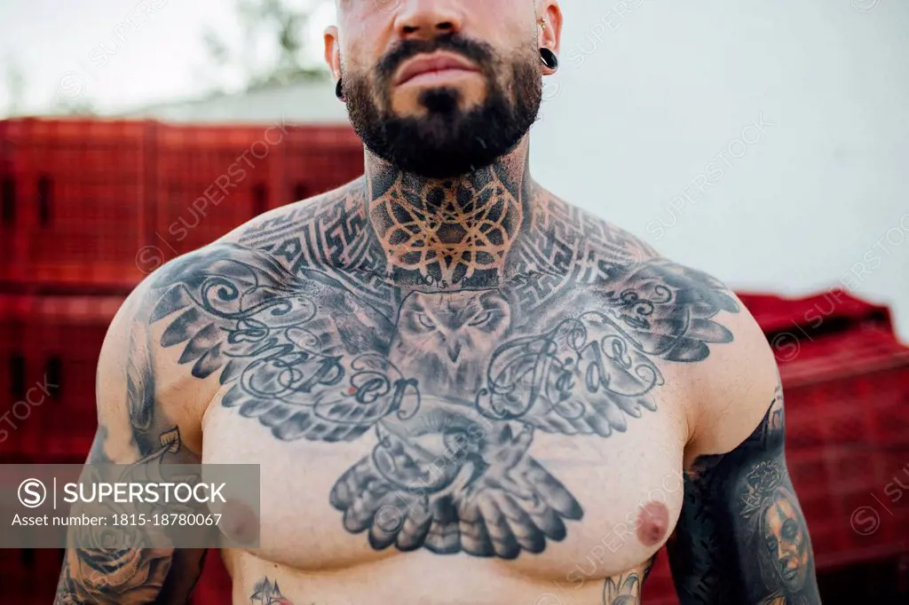 Shirtless hipster man with tattoo on neck and chest