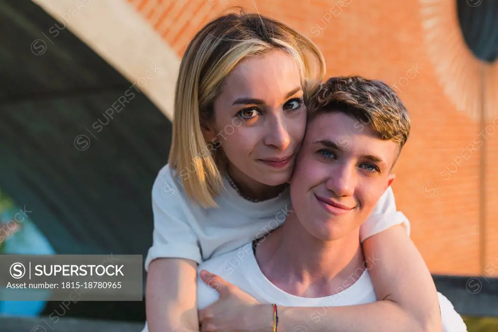 Blond woman hugging girlfriend from behind at sunset