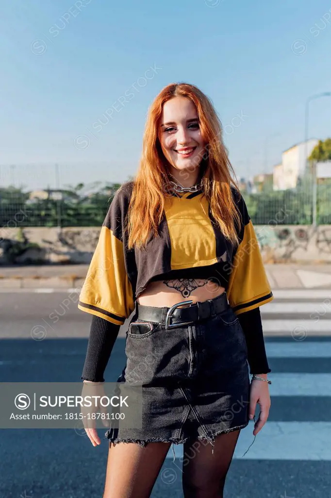Smiling redhead woman standing on road