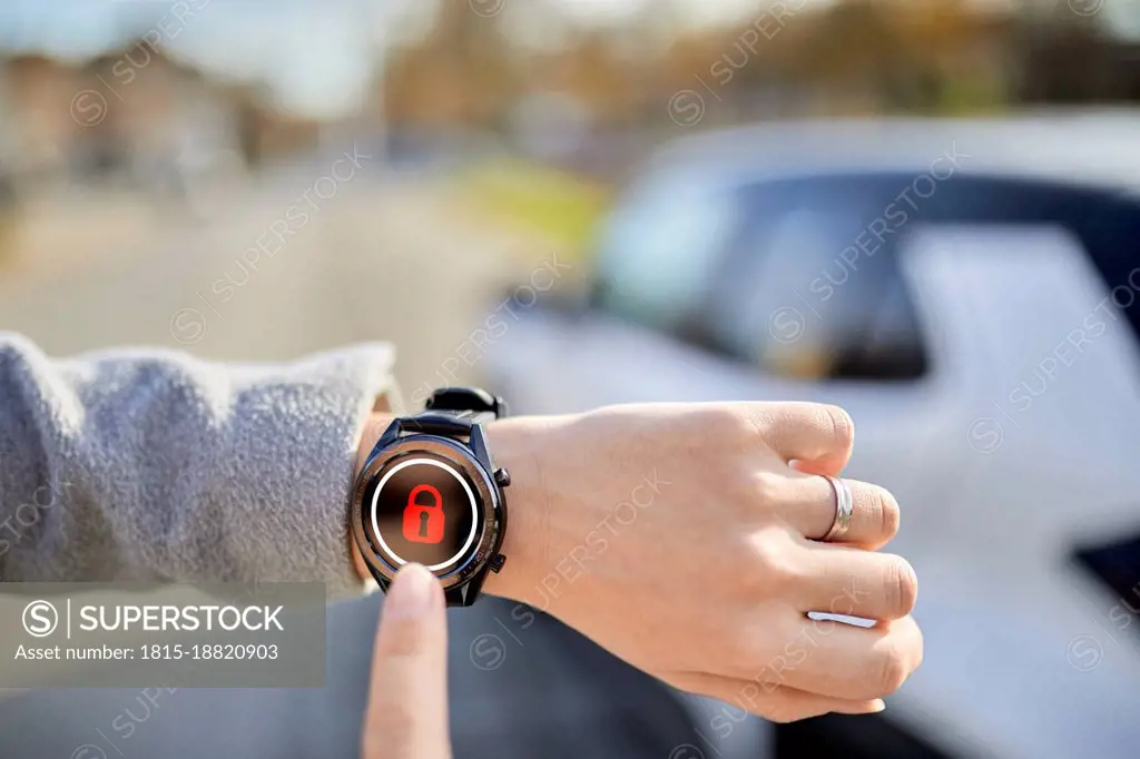 Woman locking car with smart watch on sunny day