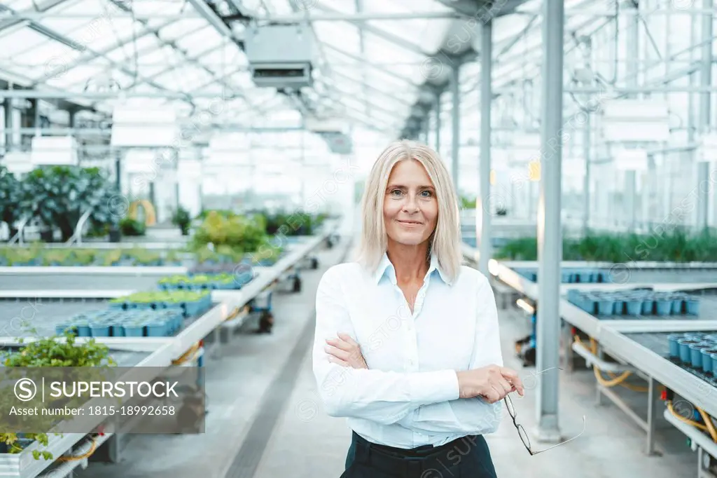 Confident scientist with arms crossed in plant nursery