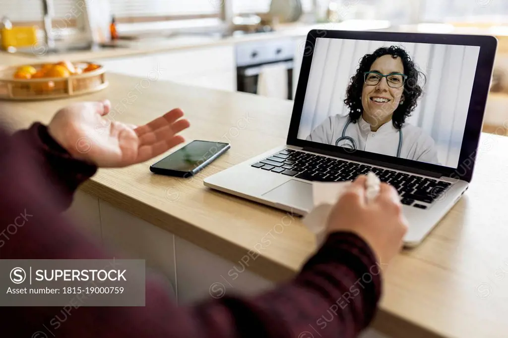 Woman doing video call with doctor on laptop at home