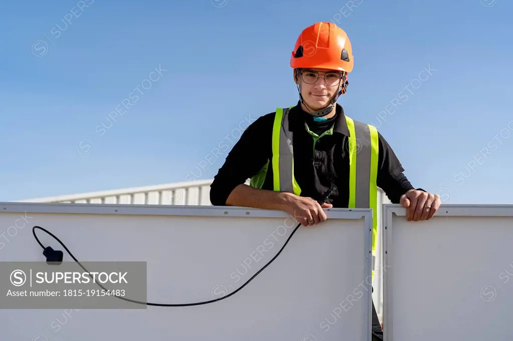 Technician with helmet standing by solar panel