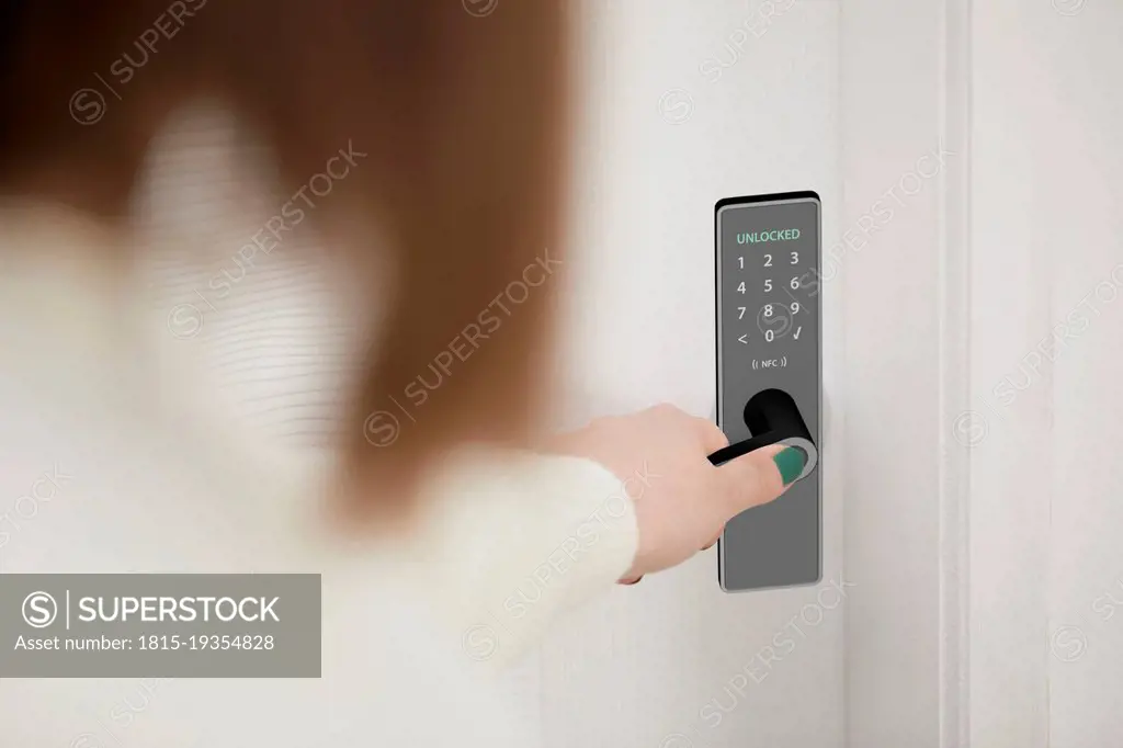 Woman unlocking smart door of house with access of fingerprint