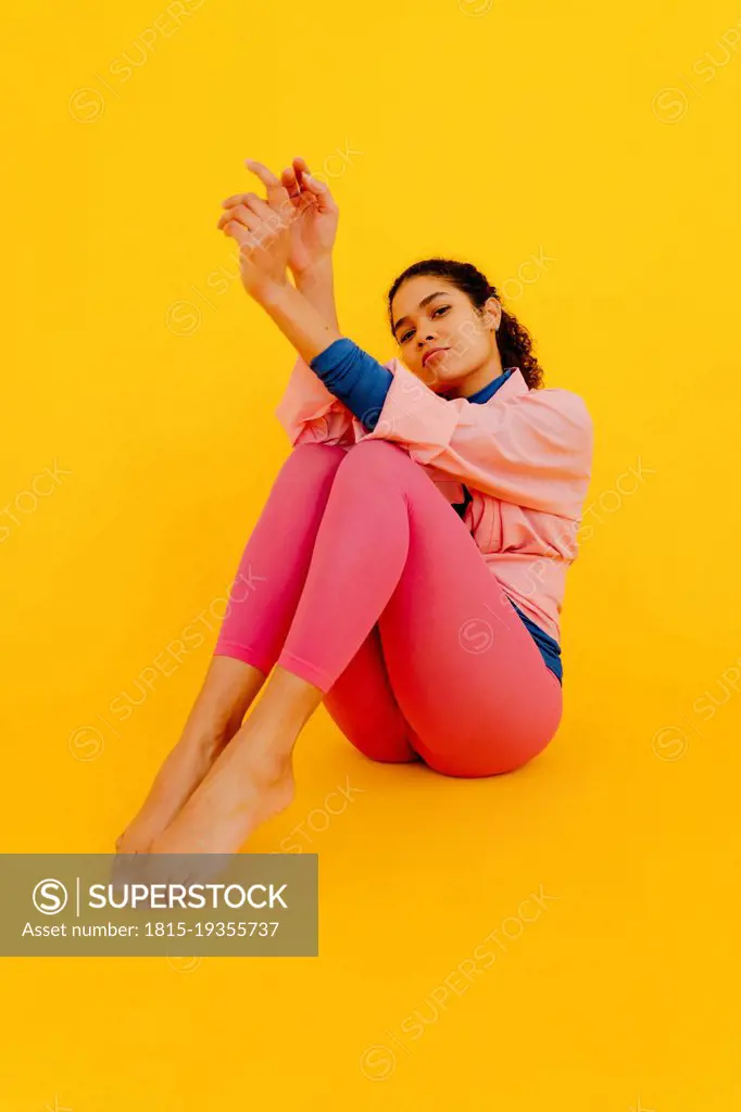 Beautiful woman sitting against yellow background