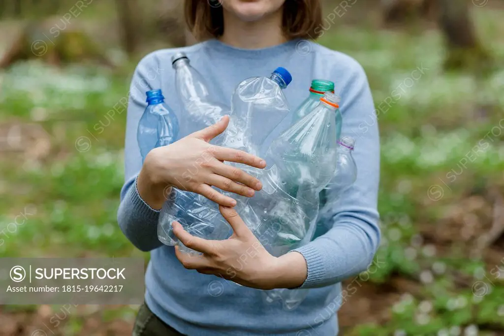 Woman carrying plastic bottles collected in forest