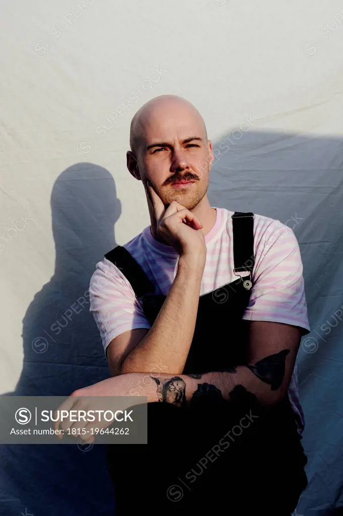 Bald man sitting in front of white backdrop