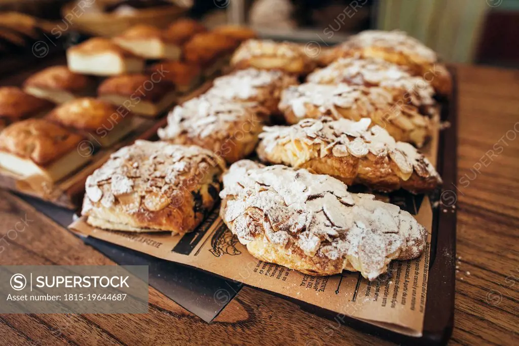 Freshly baked almond croissants with powdered sugar arranged on tray in bakery