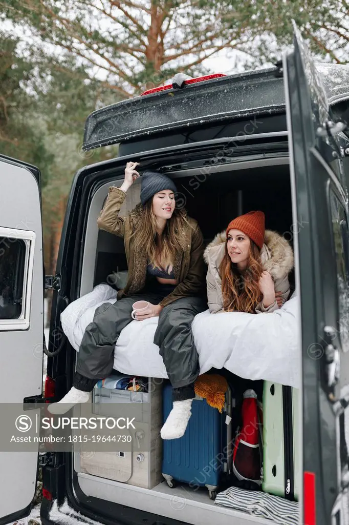 Woman talking with friend lying in campervan