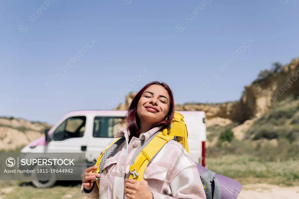Smiling woman with backpack enjoying sunny day