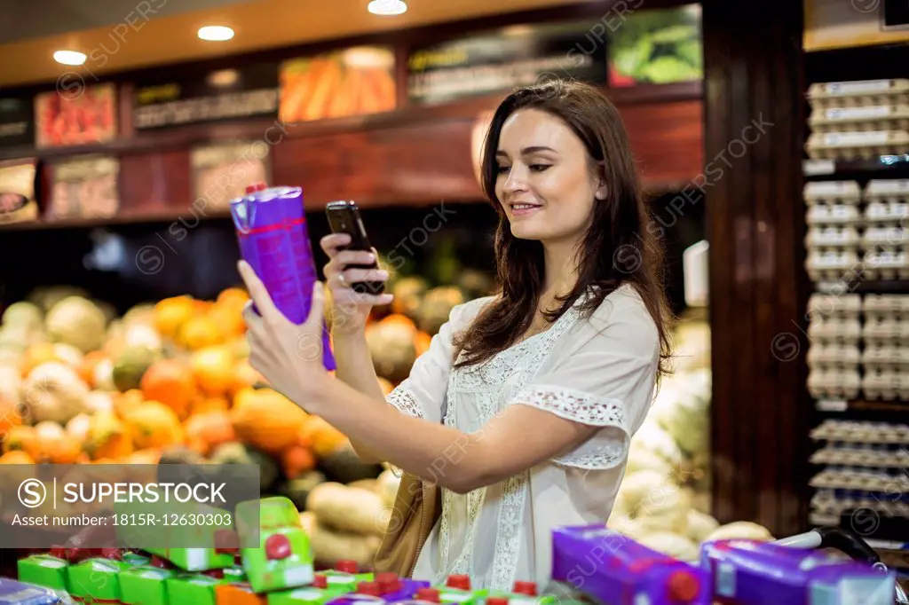 Woman at supermarket scanning prices with her smart phone