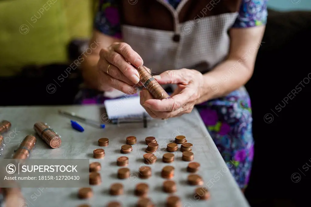 Elderly woman counting money, making stacks of Euro cents