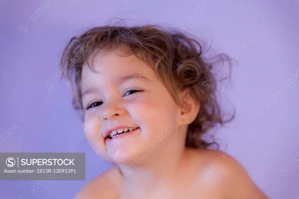 Portrait of smiling little girl in front of purple background