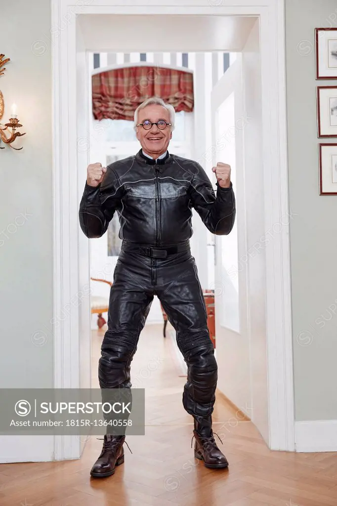 Happy senior man in motorcycle suit at home