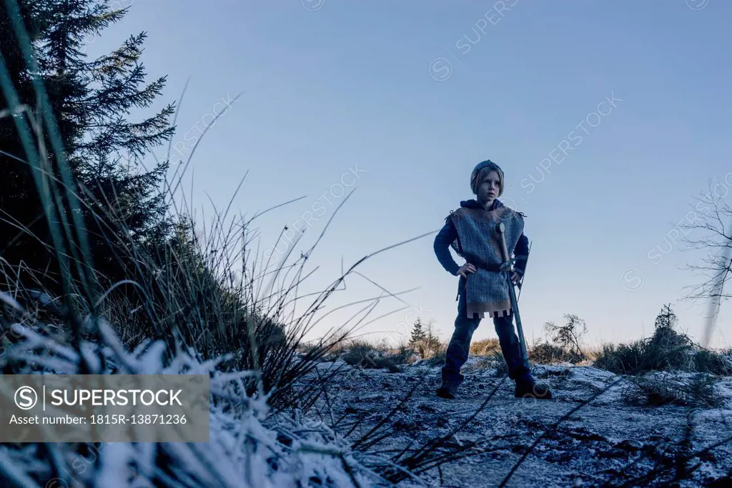 Little boy standing on a hill playing wearing knight costume