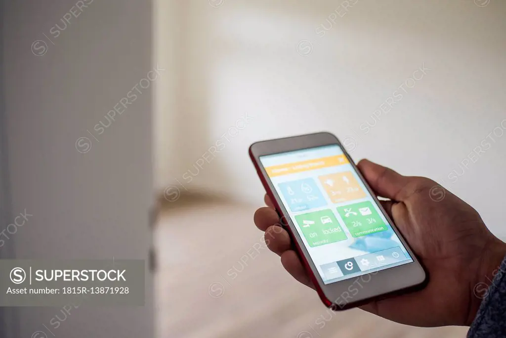 Man at home holding smartphone with smart home apps