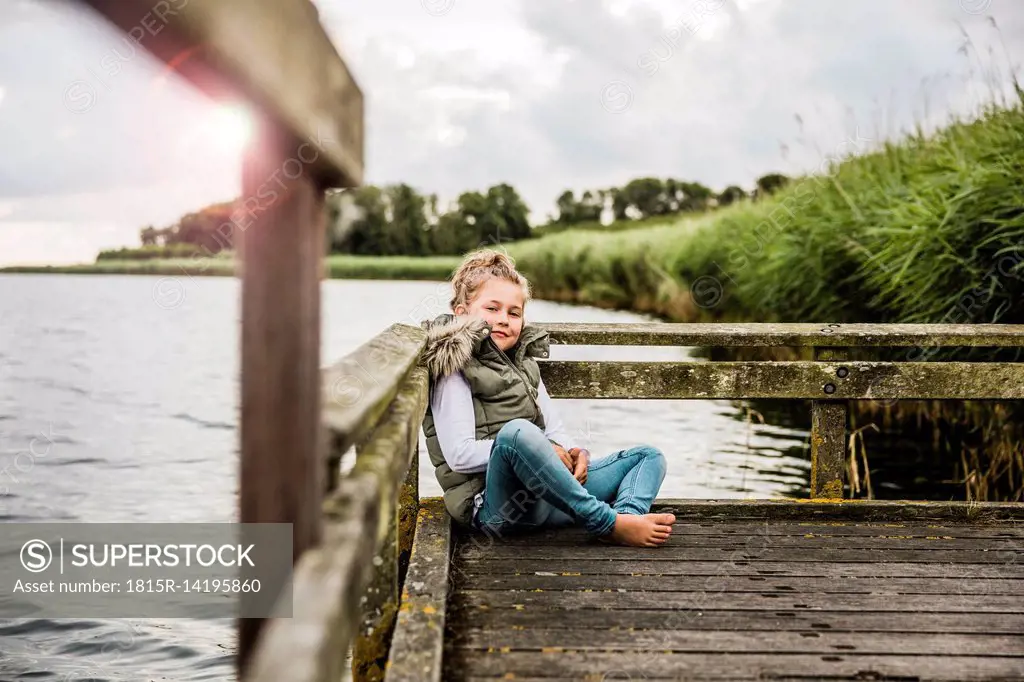 Girl sitting on jetty at a lake