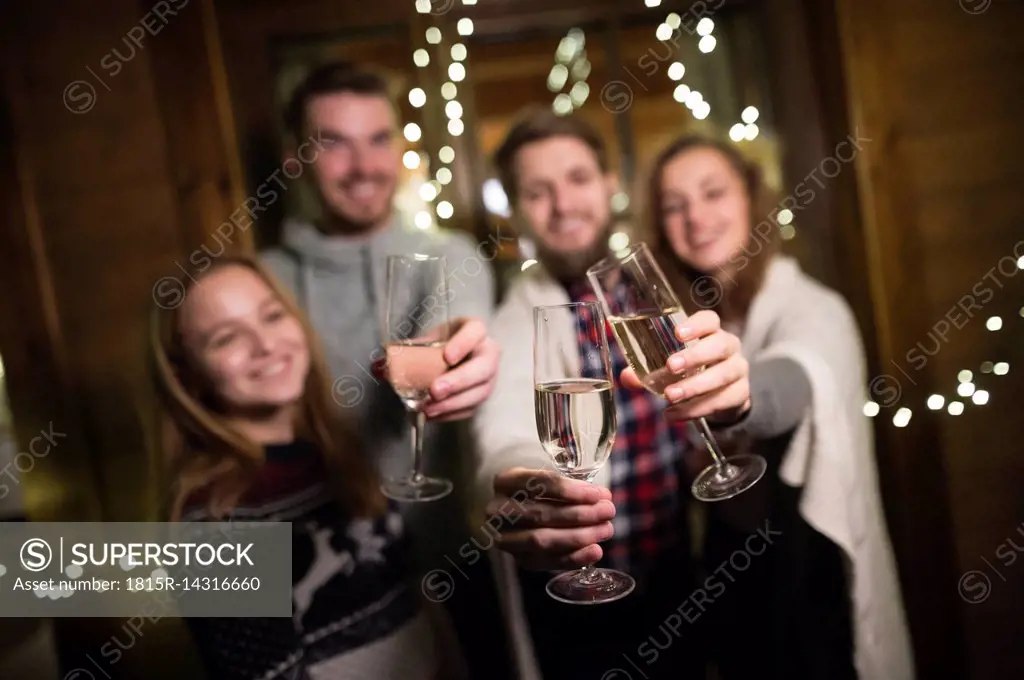 Happy friends holding champagne glasses outdoors at night