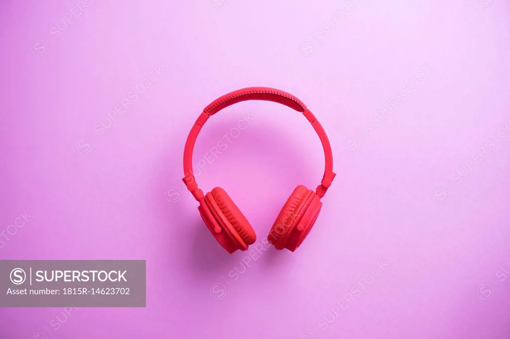 Wireless red headphones on pink background