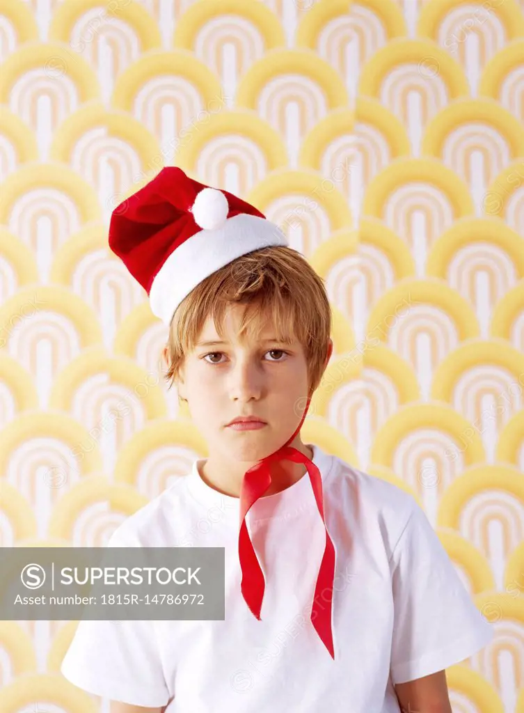 Portrait of boy in bad mood wearing Christmas cap