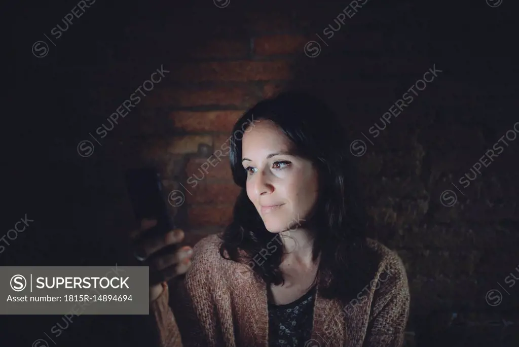 Portrait of woman using smartphone at home in the dark
