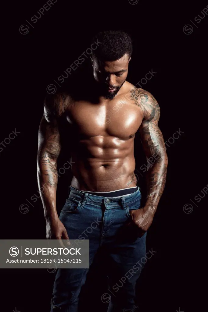 Tattooed physical athlete in front of black background