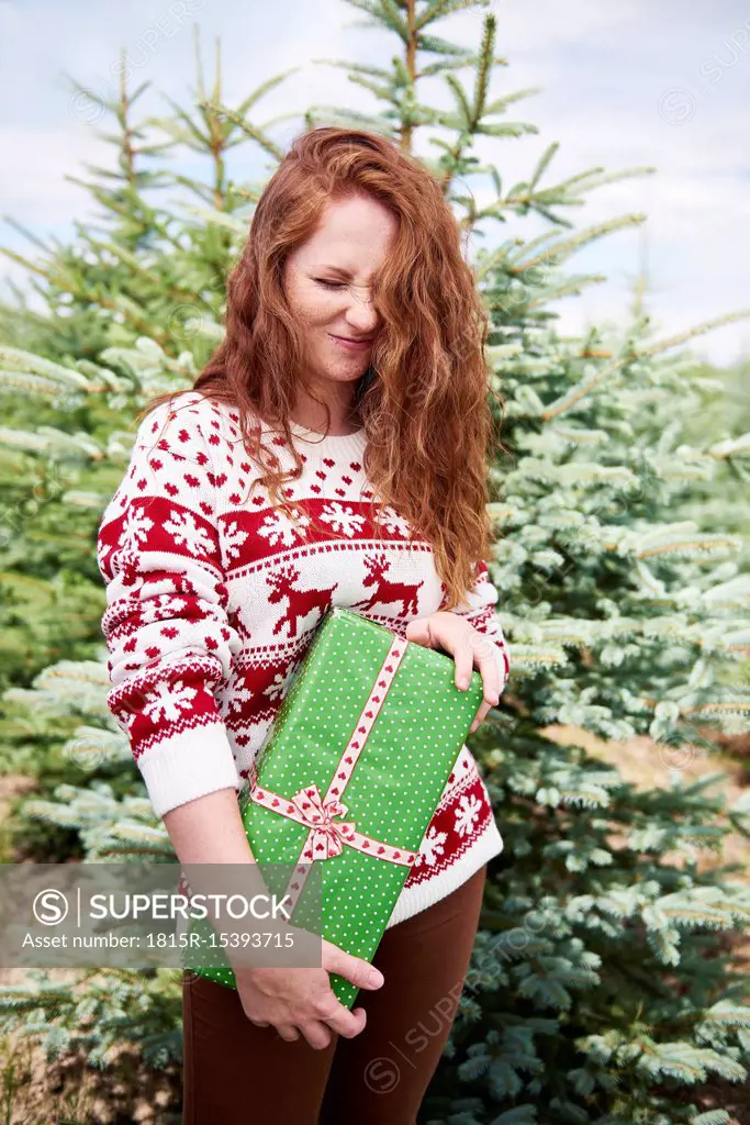 Redheaded young woman with Christmas present outdoors