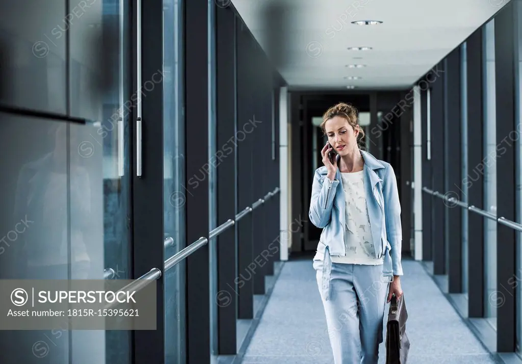 Businesswoman on cell phone walking in office passageway