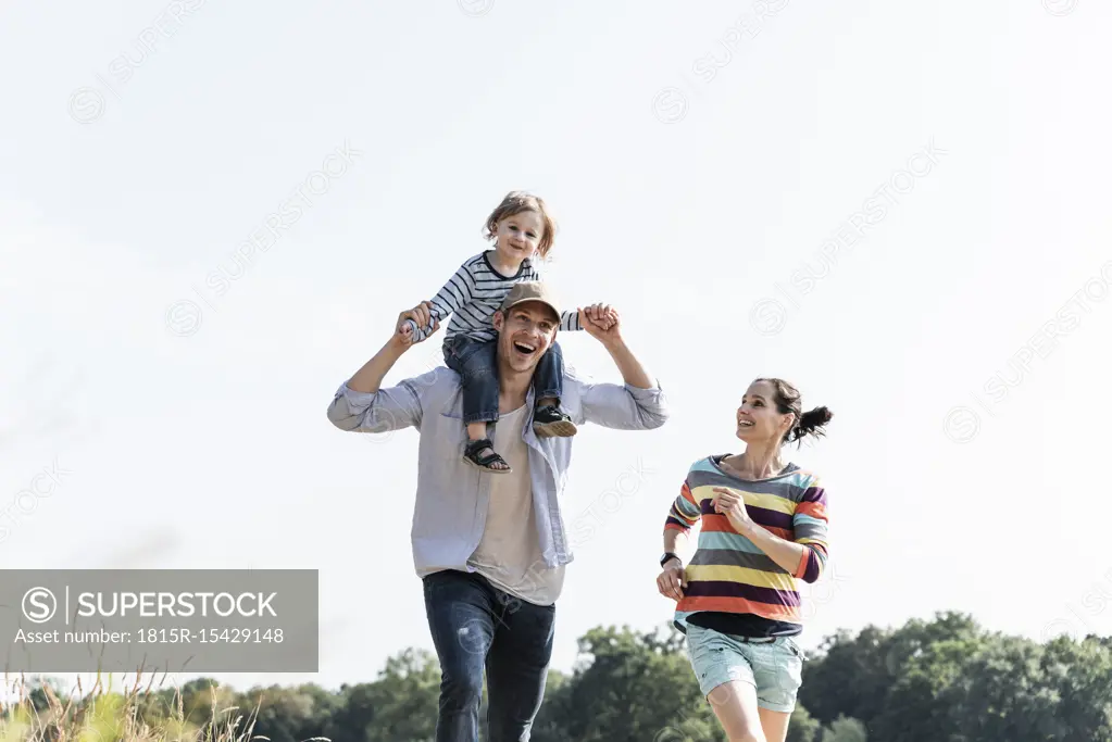 Happy family walking at the riverside on a beautiful summer day
