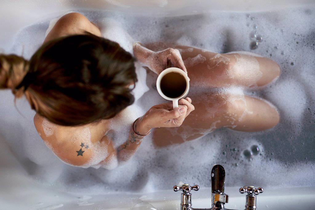 Woman having a relaxing bath and a cup of coffee in the bathtub