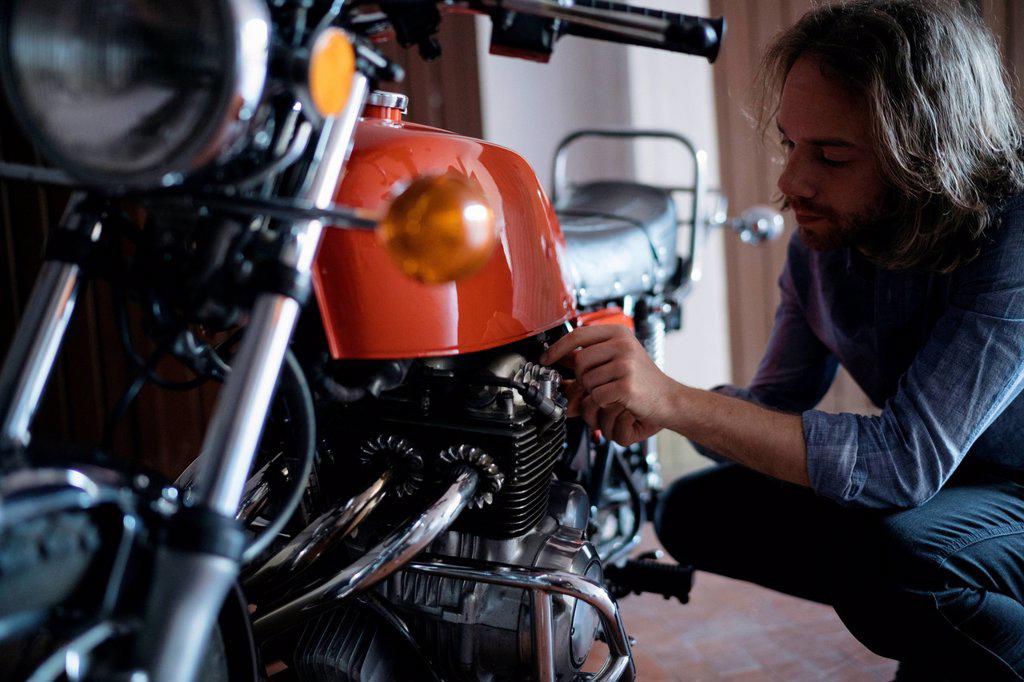 Young man checking his vintage motorbike parked in garage