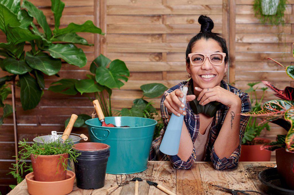 Portrait of a smiling young woman gardening on her terrace