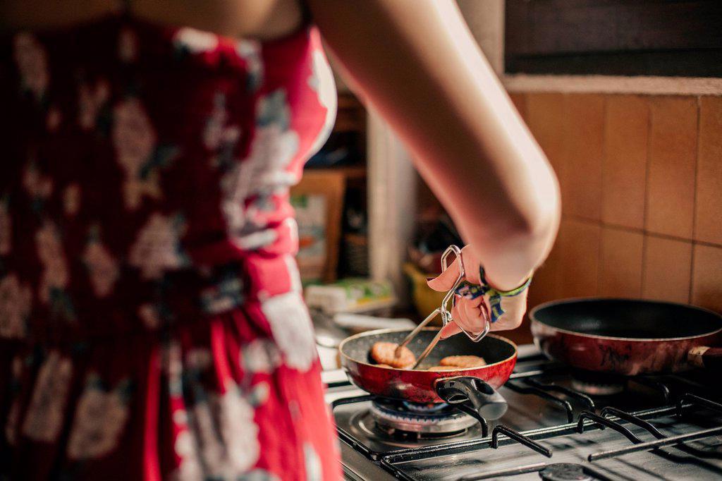 Close-up of woman cooking in kitchen using a pan
