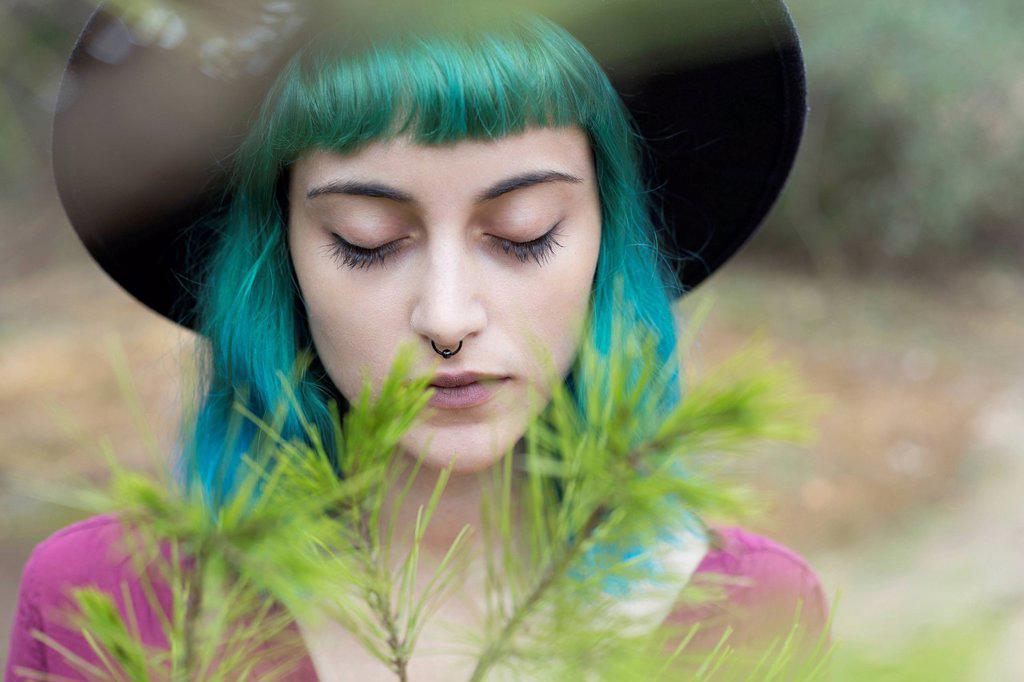 Portrait of young woman with dyed blue and green hair and nose piercing in nature