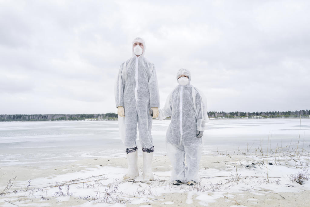 Father and son wearing protective suits standing at frozen river