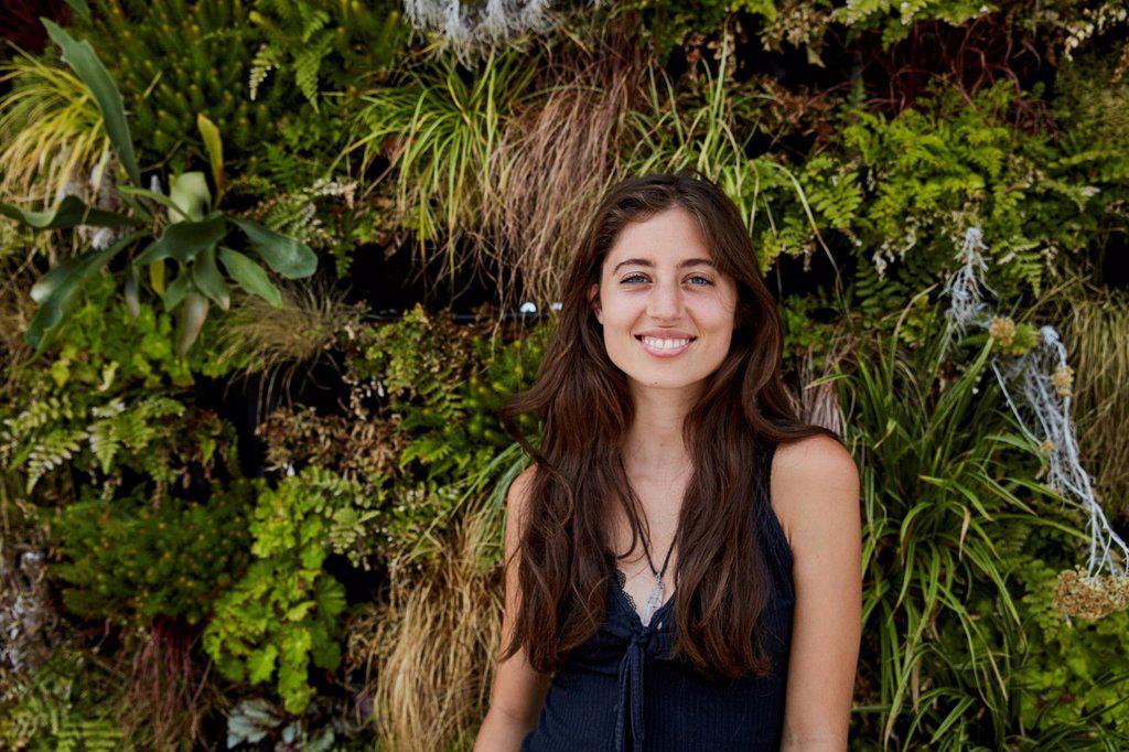 Portrait of smiling young woman in front of plant wall