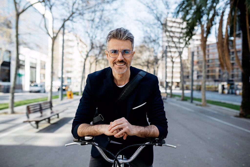 Portrait of a gray-haired businessman with bicycle in the city