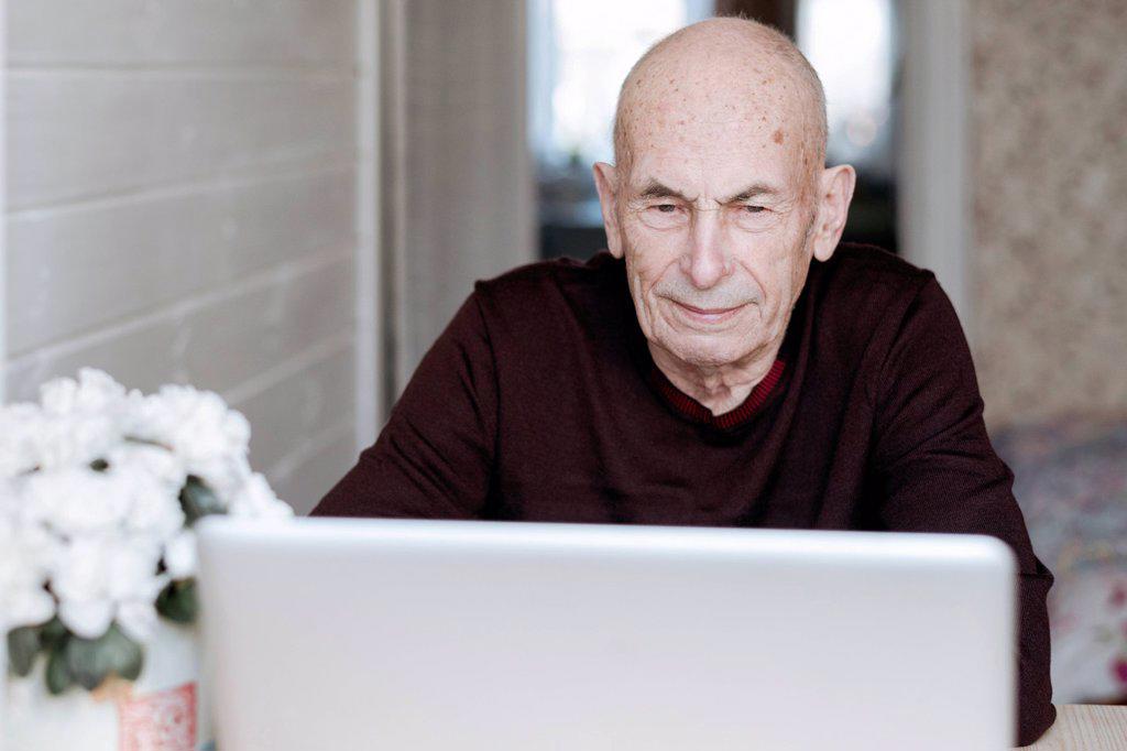 Portrait of an old man looking at laptop
