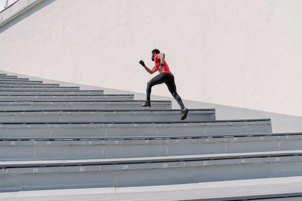 Sportsman wearing face mask running up stairs