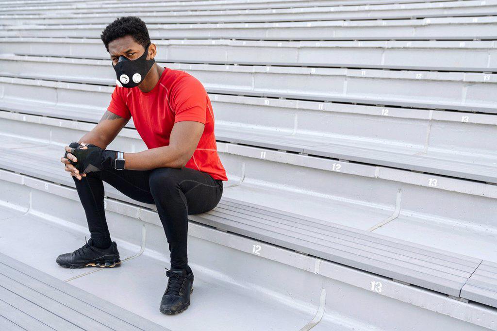 Sportsman wearing face mask sitting on stairs
