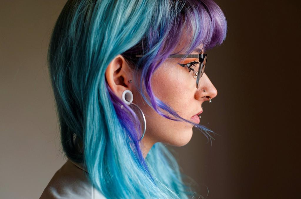 Close-up of thoughtful young woman with dyed hair and piercings against wall in old office