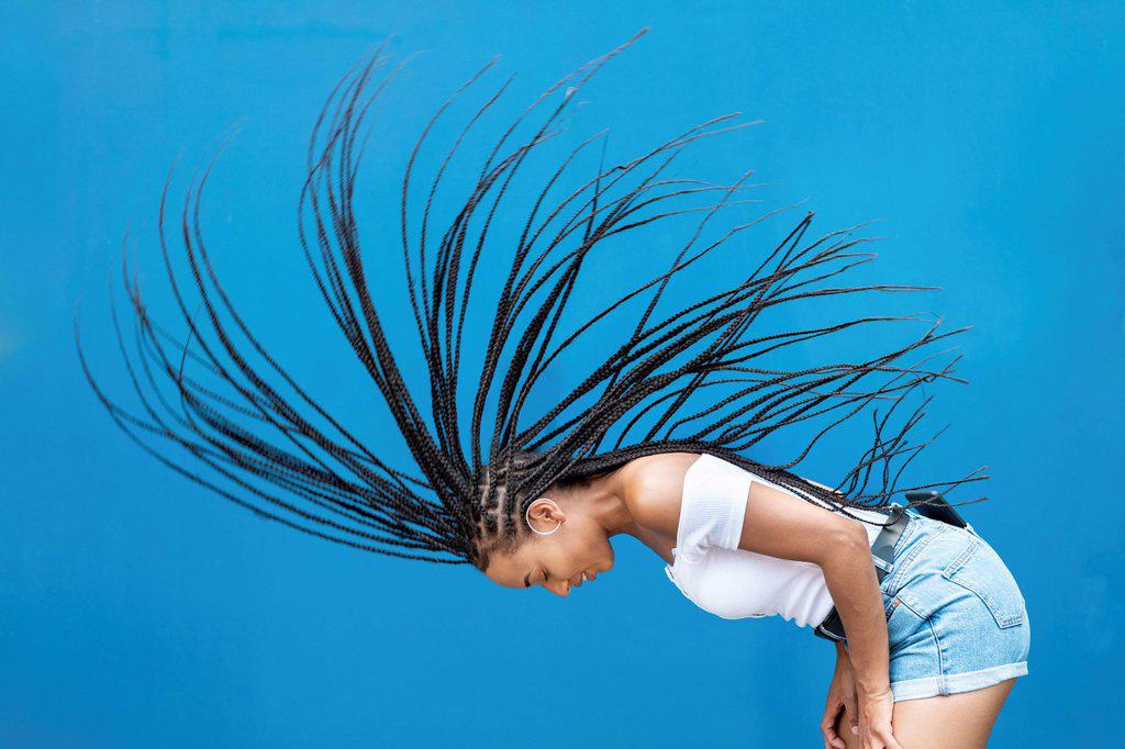 Woman tossing hair against blue wall
