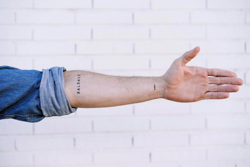 Man's hand with tattoo against brick wall