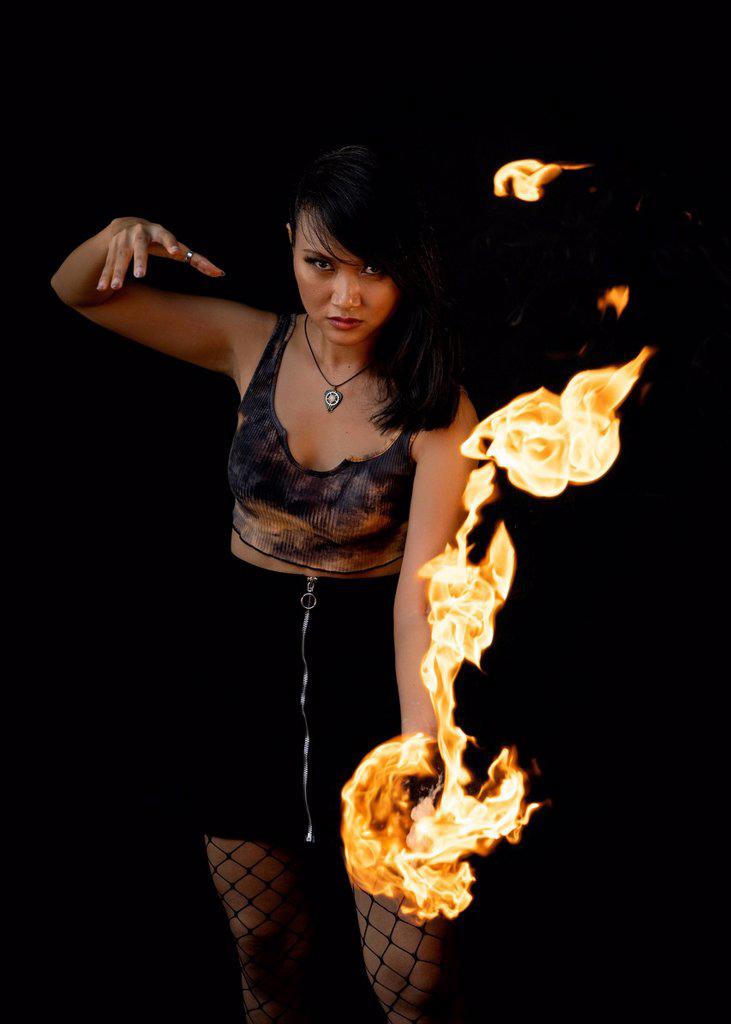 Female fire dancer performing against black background