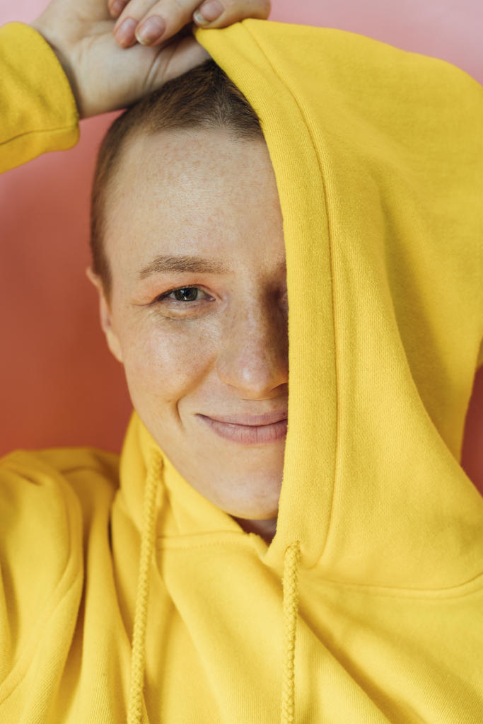 Young woman covering half face with hoodie in studio