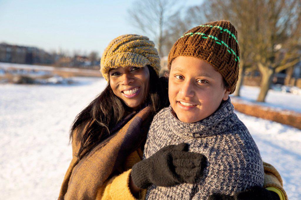 Smiling mother and son wearing knit hat standing together during winter